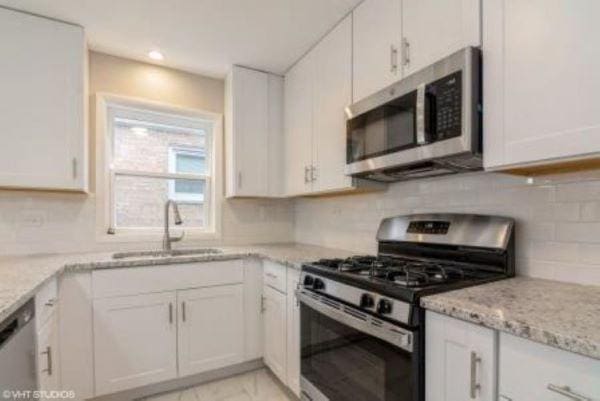 kitchen with appliances with stainless steel finishes, white cabinets, and a sink