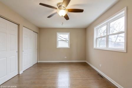 unfurnished bedroom featuring wood finished floors, visible vents, a ceiling fan, baseboards, and two closets