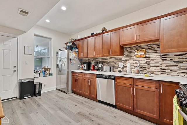 kitchen with decorative backsplash, light hardwood / wood-style flooring, and appliances with stainless steel finishes