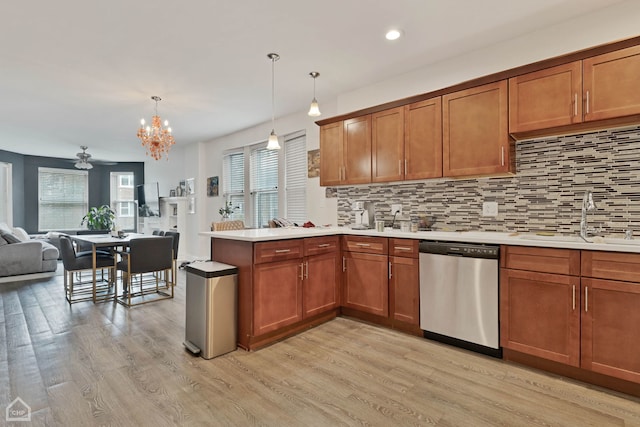 kitchen with brown cabinets, a peninsula, light countertops, stainless steel dishwasher, and a sink