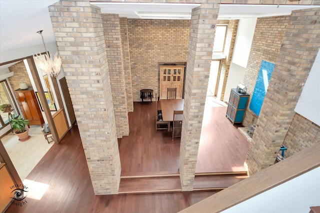 interior space featuring dark wood-type flooring, a high ceiling, and brick wall