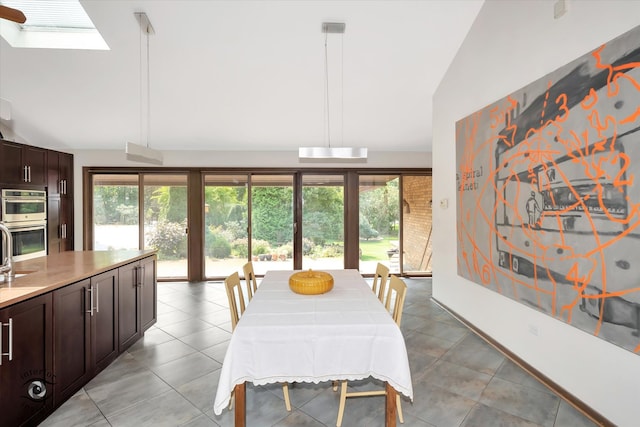 dining area featuring plenty of natural light, vaulted ceiling with skylight, and light tile patterned floors