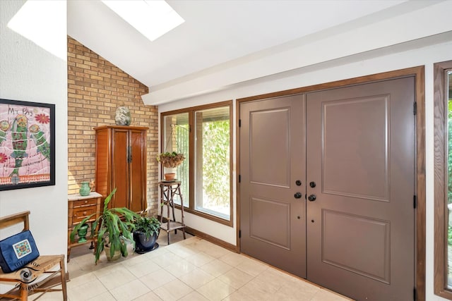 entryway featuring a wealth of natural light, vaulted ceiling with skylight, and light tile patterned flooring