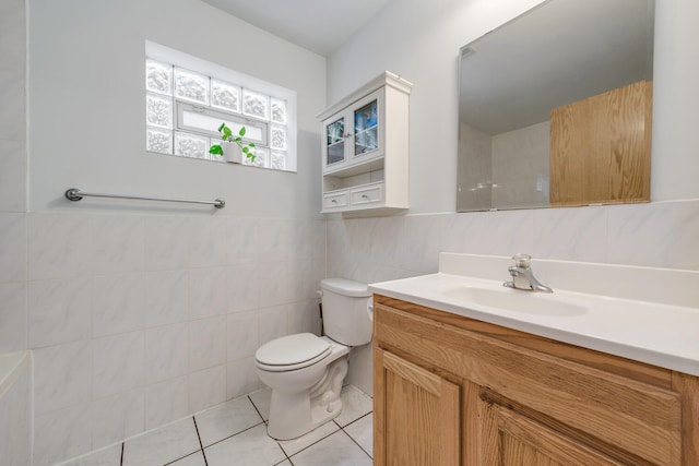 bathroom featuring vanity, toilet, tile patterned flooring, and tile walls