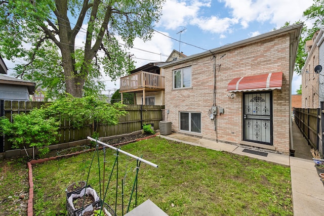 back of property featuring a yard, central AC unit, and a balcony