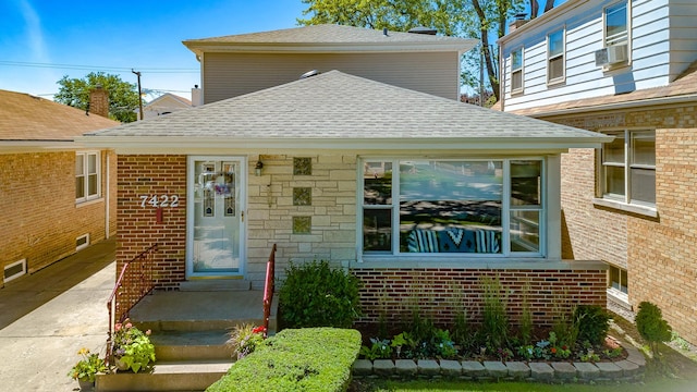 view of front of house featuring cooling unit, a shingled roof, and brick siding