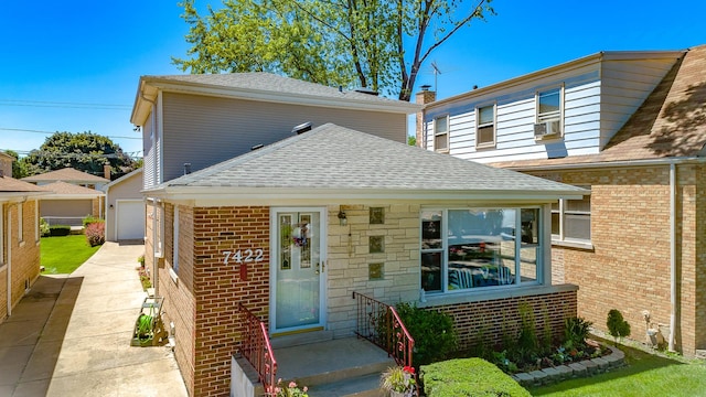 bungalow featuring a shingled roof, brick siding, and a garage