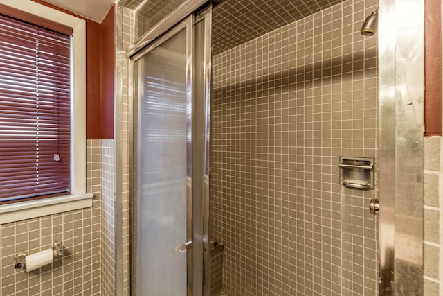 bathroom with a shower with door and tile walls