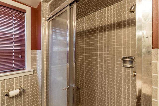 full bathroom featuring a stall shower and tile walls