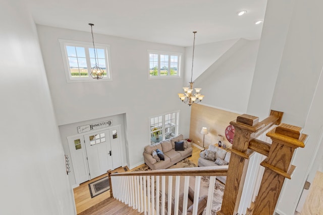 entrance foyer featuring a notable chandelier, wood finished floors, a towering ceiling, baseboards, and stairway