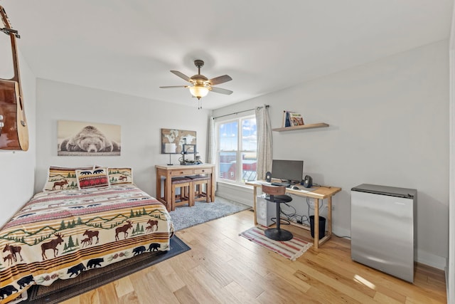 bedroom featuring ceiling fan, wood finished floors, stainless steel fridge, and baseboards