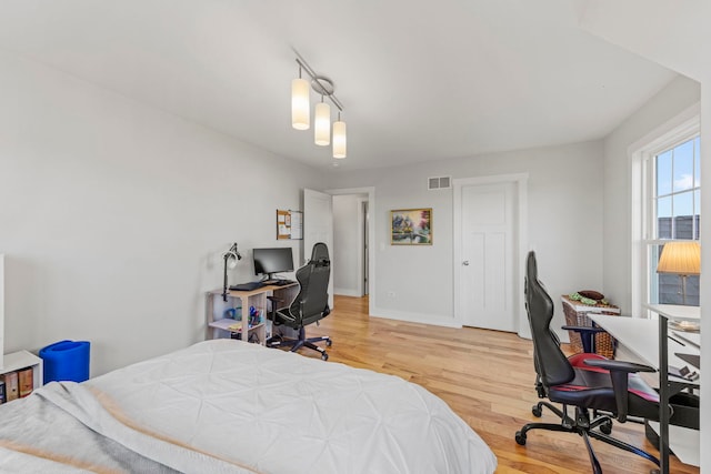 bedroom featuring light wood-style flooring, visible vents, and baseboards