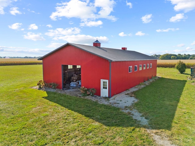 view of outbuilding with a lawn and a rural view