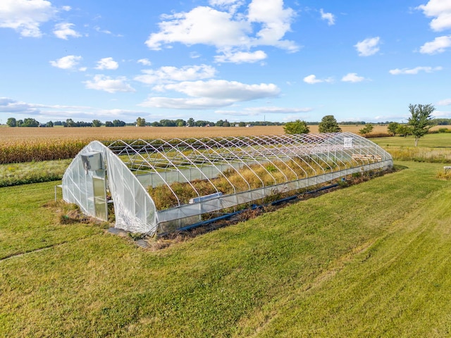 exterior space featuring a greenhouse, a yard, a rural view, and an outdoor structure