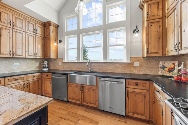 kitchen featuring stainless steel dishwasher, a sink, light wood-style flooring, and decorative backsplash