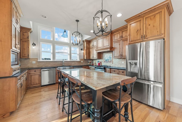 kitchen featuring appliances with stainless steel finishes, a breakfast bar area, dark stone countertops, and light wood-style flooring