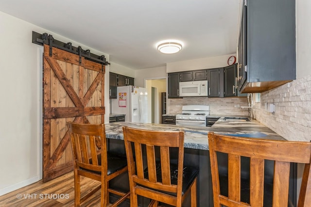 15312 Sunshine Cir, Plainfield, IL 60544 - kitchen featuring white appliances, tasteful backsplash, wood finished floors, a peninsula, and a barn door