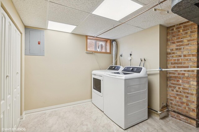 laundry area with brick wall, washer and clothes dryer, and electric panel