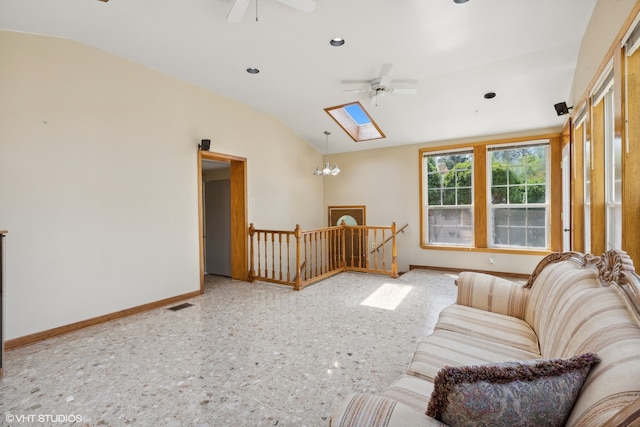 living room with vaulted ceiling with skylight and ceiling fan with notable chandelier