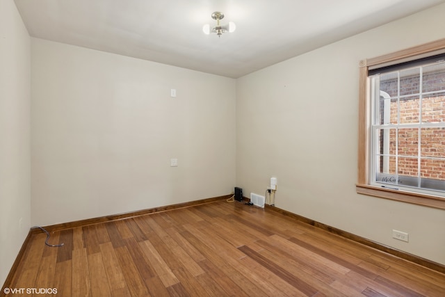 spare room featuring hardwood / wood-style floors and a chandelier