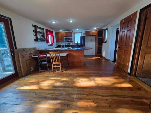 kitchen featuring kitchen peninsula, plenty of natural light, dark hardwood / wood-style floors, and a breakfast bar