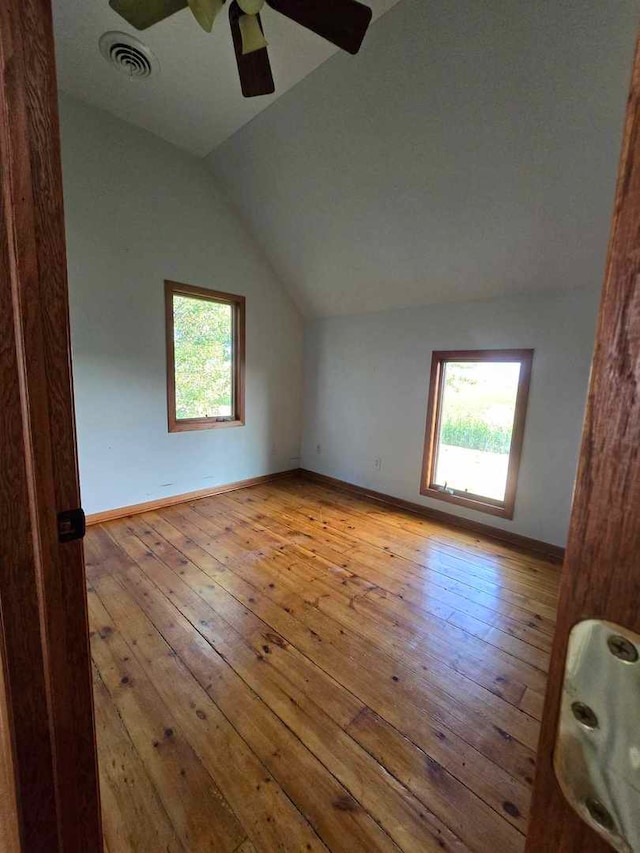 additional living space with light wood-type flooring, lofted ceiling, a healthy amount of sunlight, and ceiling fan