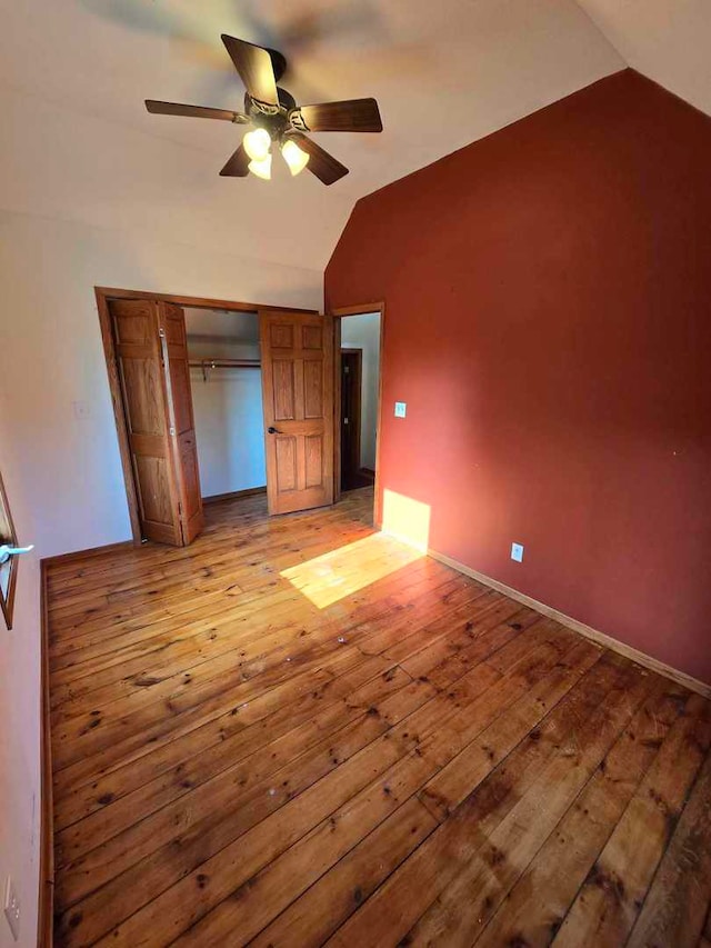 unfurnished bedroom featuring ceiling fan, a closet, light hardwood / wood-style flooring, and vaulted ceiling