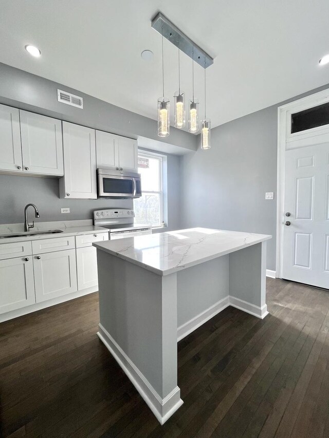 kitchen with white electric range oven, black fridge, pendant lighting, a kitchen island, and white cabinetry