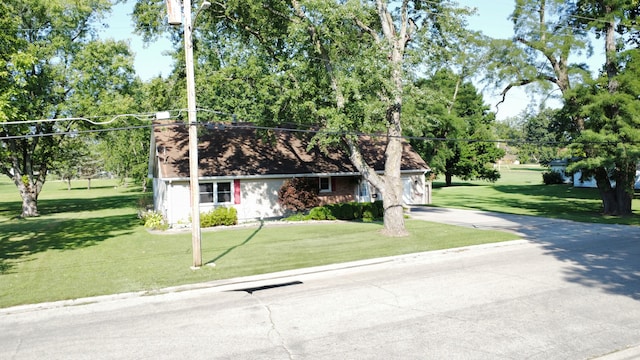 view of front of house featuring an attached garage, a front lawn, concrete driveway, and brick siding