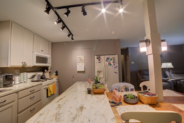 kitchen with rail lighting, light hardwood / wood-style floors, light stone counters, and white appliances