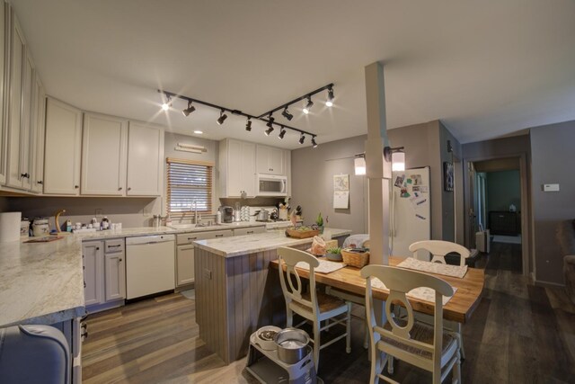 kitchen featuring white cabinetry, rail lighting, dark hardwood / wood-style floors, light stone countertops, and white appliances