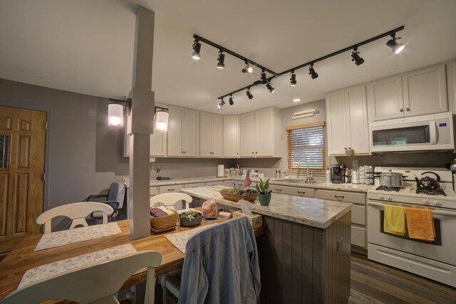 kitchen with rail lighting, sink, dark wood-type flooring, and white appliances