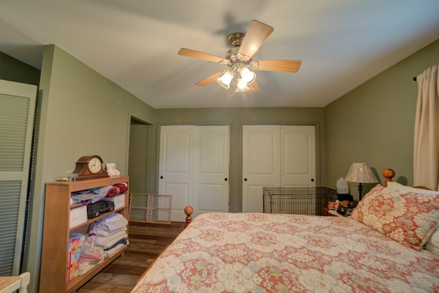 bedroom featuring ceiling fan, multiple closets, and dark wood-type flooring