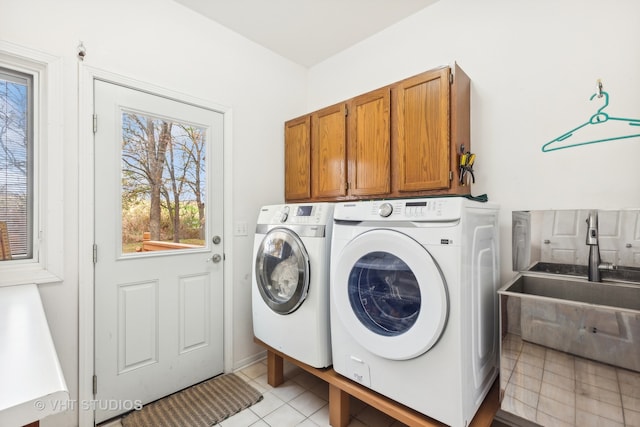 clothes washing area with washing machine and clothes dryer, light tile patterned floors, and cabinets