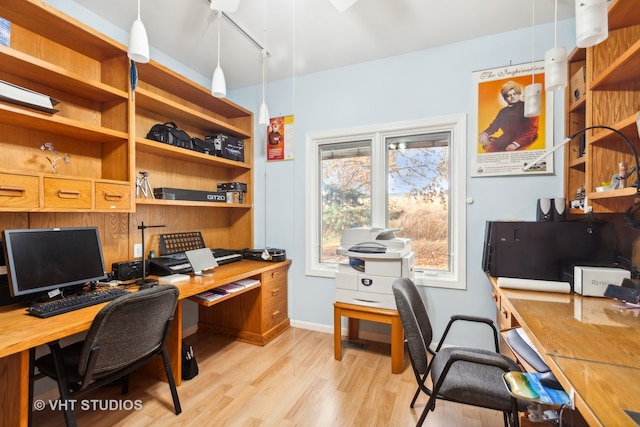 home office with light hardwood / wood-style flooring and rail lighting