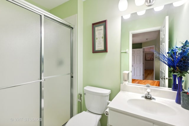 bathroom featuring vanity, toilet, a shower with shower door, and hardwood / wood-style floors