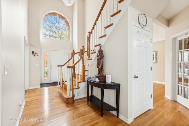 entryway with light hardwood / wood-style floors and a towering ceiling