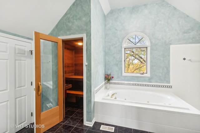 bathroom with vaulted ceiling, tiled tub, and tile patterned flooring