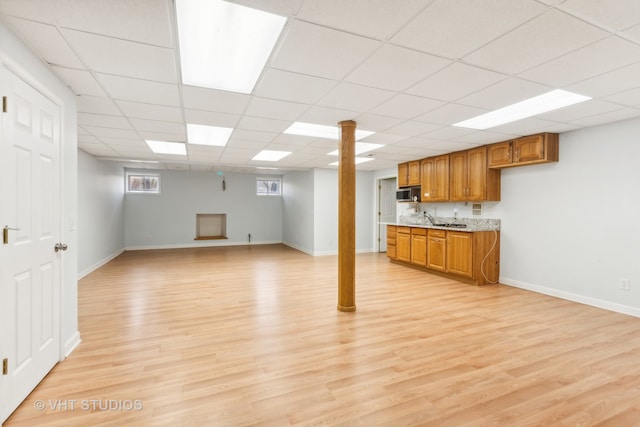 basement with a drop ceiling, light hardwood / wood-style flooring, and sink