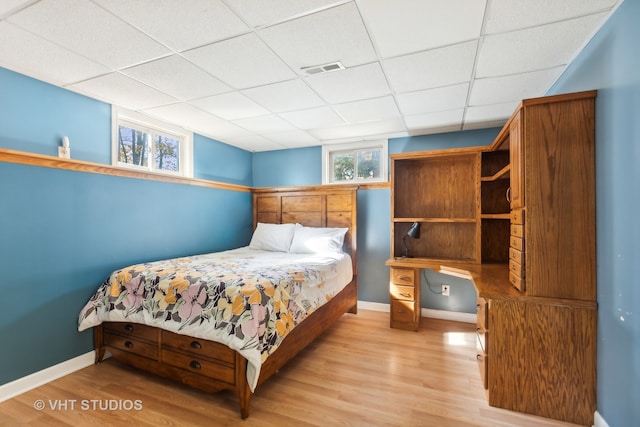 bedroom with light hardwood / wood-style floors and a paneled ceiling