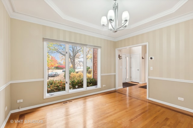 spare room featuring ornamental molding, a chandelier, and wood-type flooring