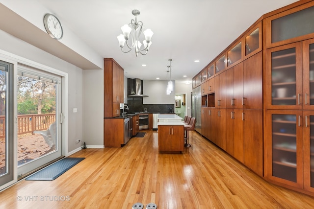 kitchen featuring light hardwood / wood-style flooring, wall chimney exhaust hood, a center island, and pendant lighting