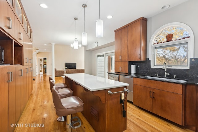 kitchen featuring light hardwood / wood-style floors, sink, hanging light fixtures, and a kitchen bar