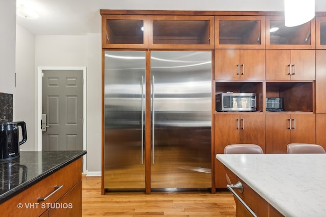 kitchen with light hardwood / wood-style floors, stainless steel appliances, and dark stone counters