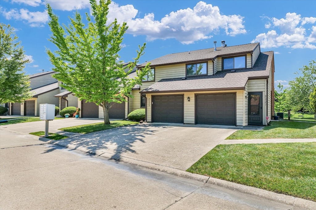 view of property featuring a garage and a front lawn