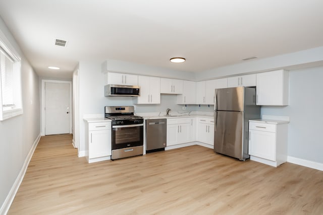 kitchen with light wood-type flooring, appliances with stainless steel finishes, sink, and white cabinets