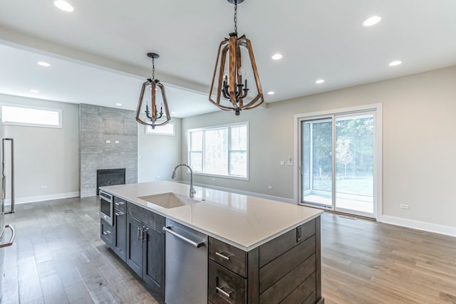 kitchen featuring a sink, light countertops, dishwasher, and an island with sink