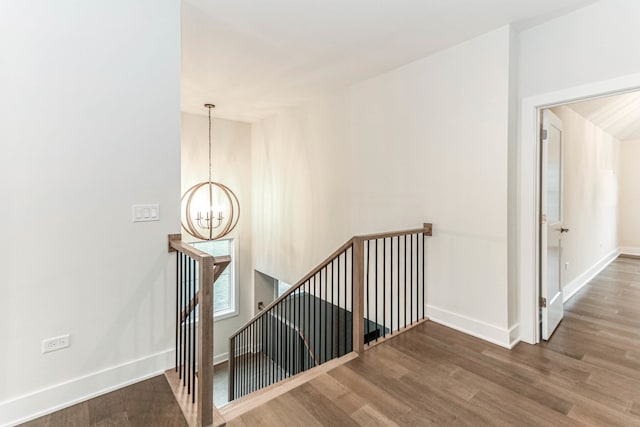 stairway featuring lofted ceiling, baseboards, a chandelier, and wood finished floors