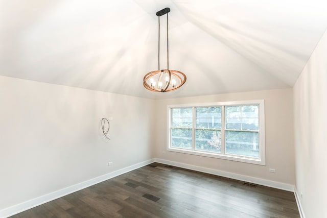 empty room with a chandelier, dark wood-type flooring, vaulted ceiling, and baseboards