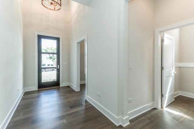 foyer with dark wood finished floors, a towering ceiling, and baseboards